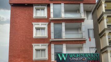 A multi-story hotel with a red brick facade, balconies, and a sign for 'Wormwood Synergy Hotels La Bella'.