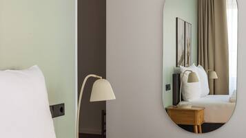 Ein Hotelzimmer mit Bett, Nachttischlampe, Schminktisch und einer Tür zu einem weiteren Raum.