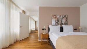 Una habitación de hotel con una cama, mesitas de noche y vistas a un pasillo.