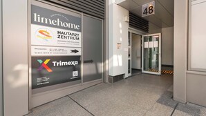 Entrada de un edificio con un letrero que anuncia los servicios de 'limhome' y 'Trimexa'.