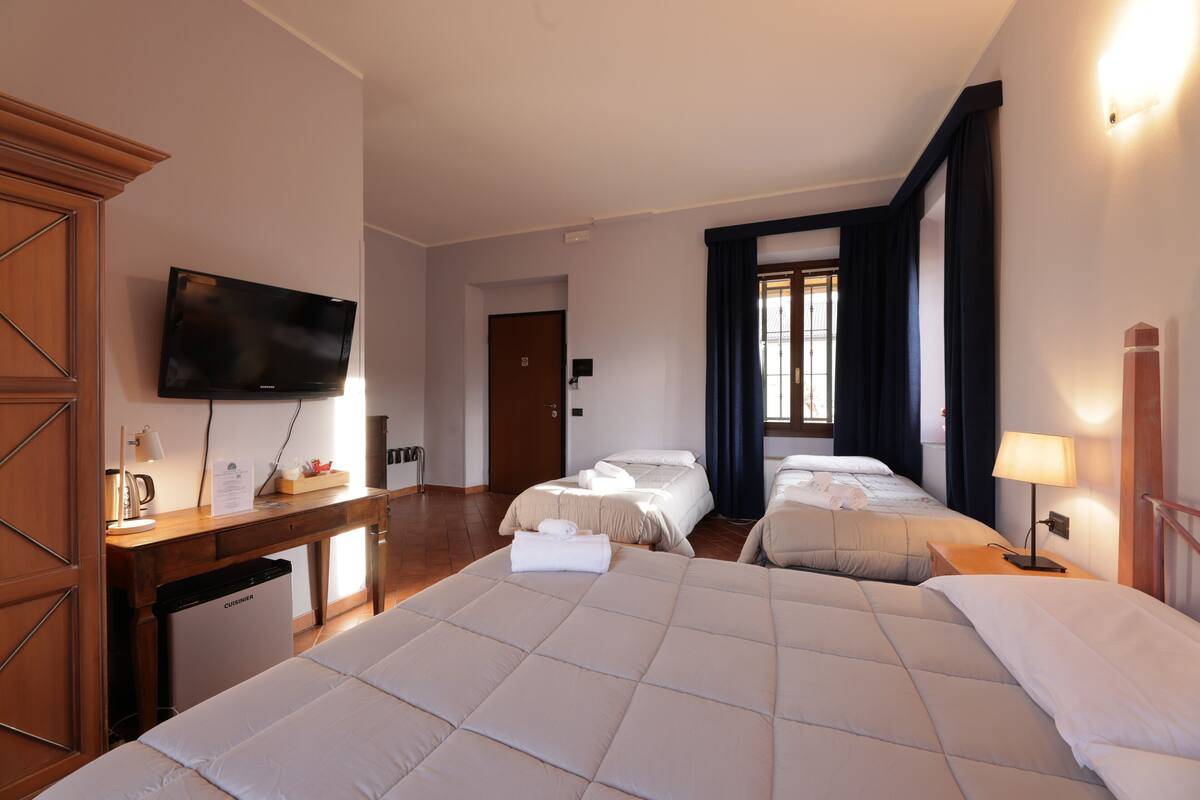 Een hotelkamer met twee bedden, een bureau met een televisie en een minibar.