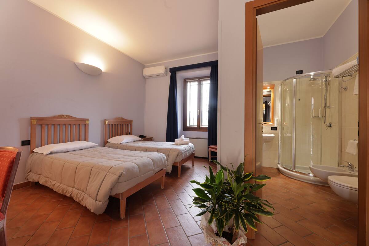 Een hotelkamer met twee bedden, een douche en een badkamer.