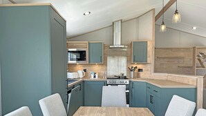 A modern kitchen with teal cabinetry, a wooden dining table, and a built-in stove.