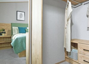 A bedroom with a bed, bedside table, dresser, and a framed picture on the wall.