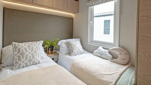 Une chambre à coucher de taille modeste, avec deux lits, une fenêtre offrant une belle vue et des armoires encastrées en bois.