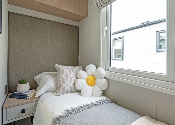 A bedroom with a bed, a nightstand, a window, and a view of buildings outside.