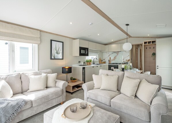 Ein modernes Wohnzimmer mit zwei Sofas, einem Couchtisch und einer Küchenzeile mit Fernseher.
