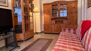 Un salon avec un téléviseur, des meubles en bois, un canapé et un lampadaire.