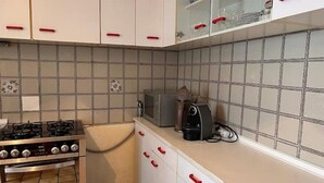 Une cuisine avec des meubles blancs, une cuisinière à gaz, un four à micro-ondes et un grille-pain.