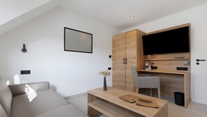 Un soggiorno moderno con un divano, un tavolino in legno, una TV montata su un mobiletto in legno e una poltrona grigia.