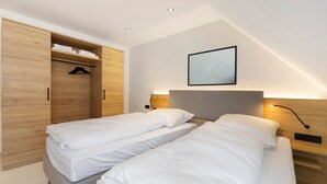 Una camera da letto con due letti, un armadio in legno, un quadro appeso al muro e un comodino con una lampada.