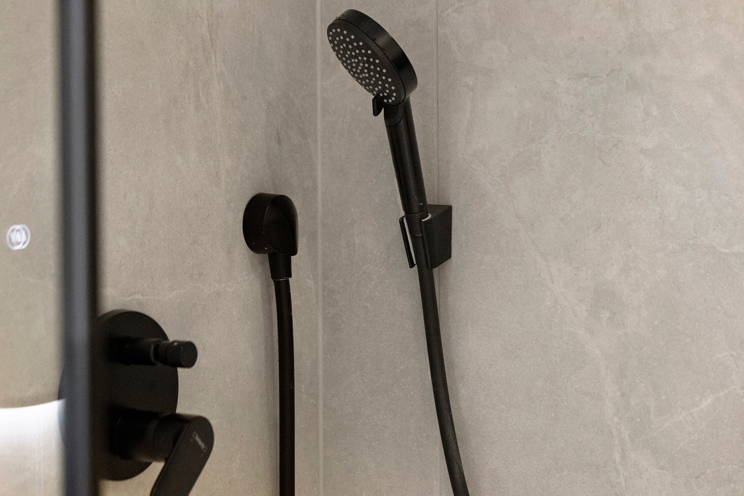 A shower with a handheld showerhead and a fixed wall-mounted showerhead.