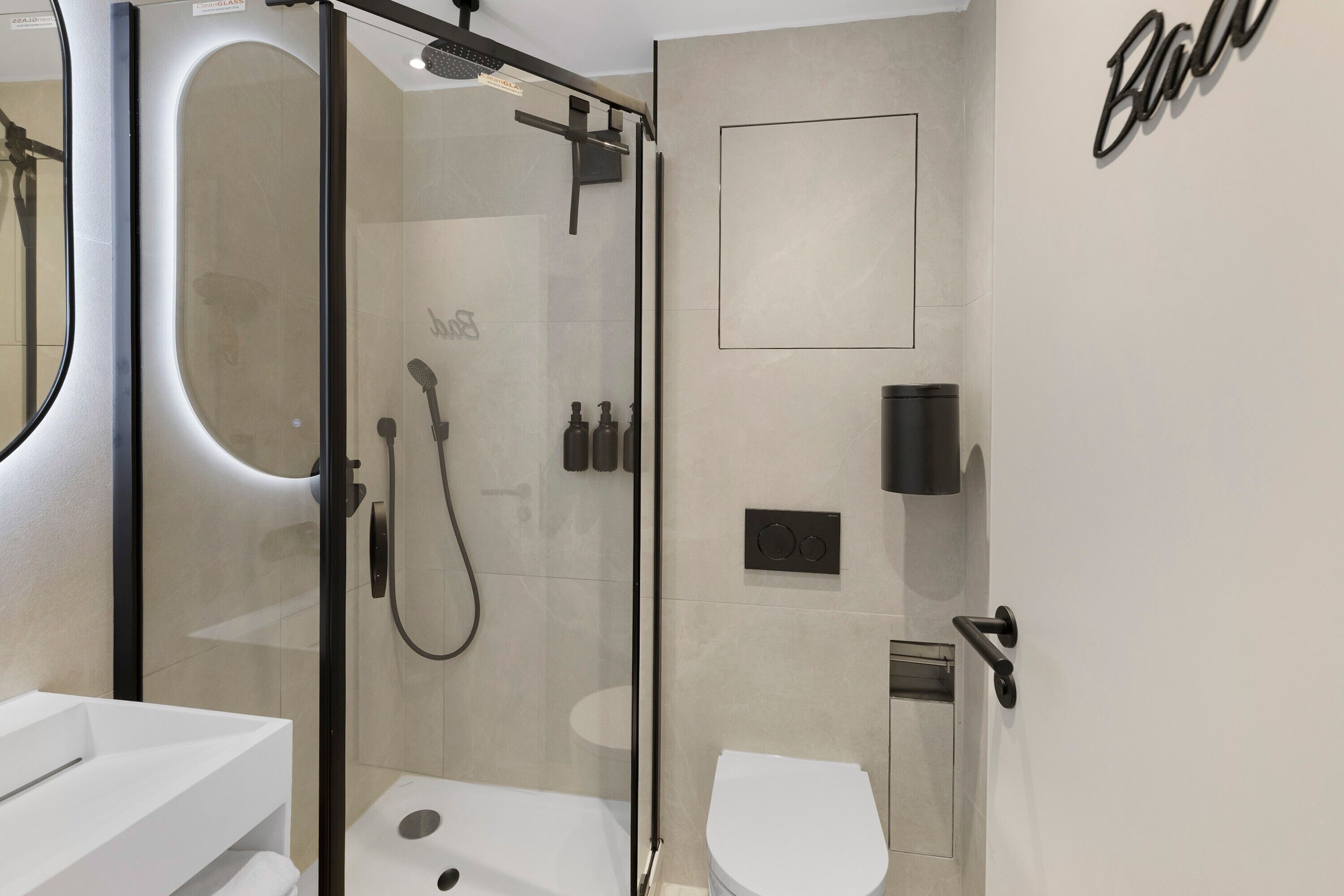 A modern bathroom with a glass-enclosed shower, a white toilet, and a sink.