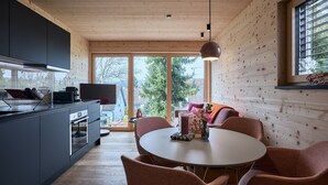 Una cocina moderna con armarios oscuros, una mesa redonda y sillas rosas.