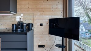 Una cocina moderna con paneles de madera, un televisor de pantalla plana grande y una cafetera.