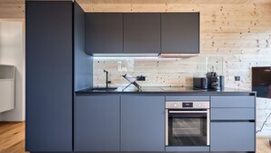 Una cocina moderna con horno empotrado, un lavamanos y un microondas.