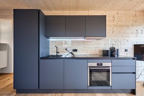 Cozinha moderna com forno embutido, pia e micro-ondas.