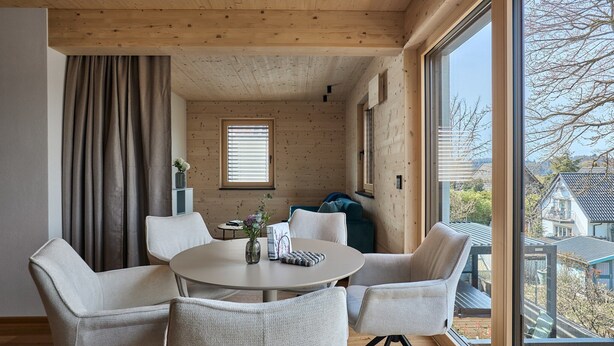 Un intérieur moderne avec une table ronde, des chaises, une fenêtre et une vue sur l’extérieur.