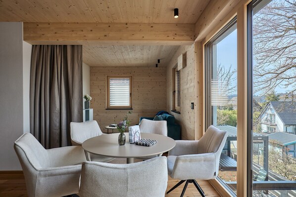 A modern interior with a round table, chairs, a window, and a view of the outside.