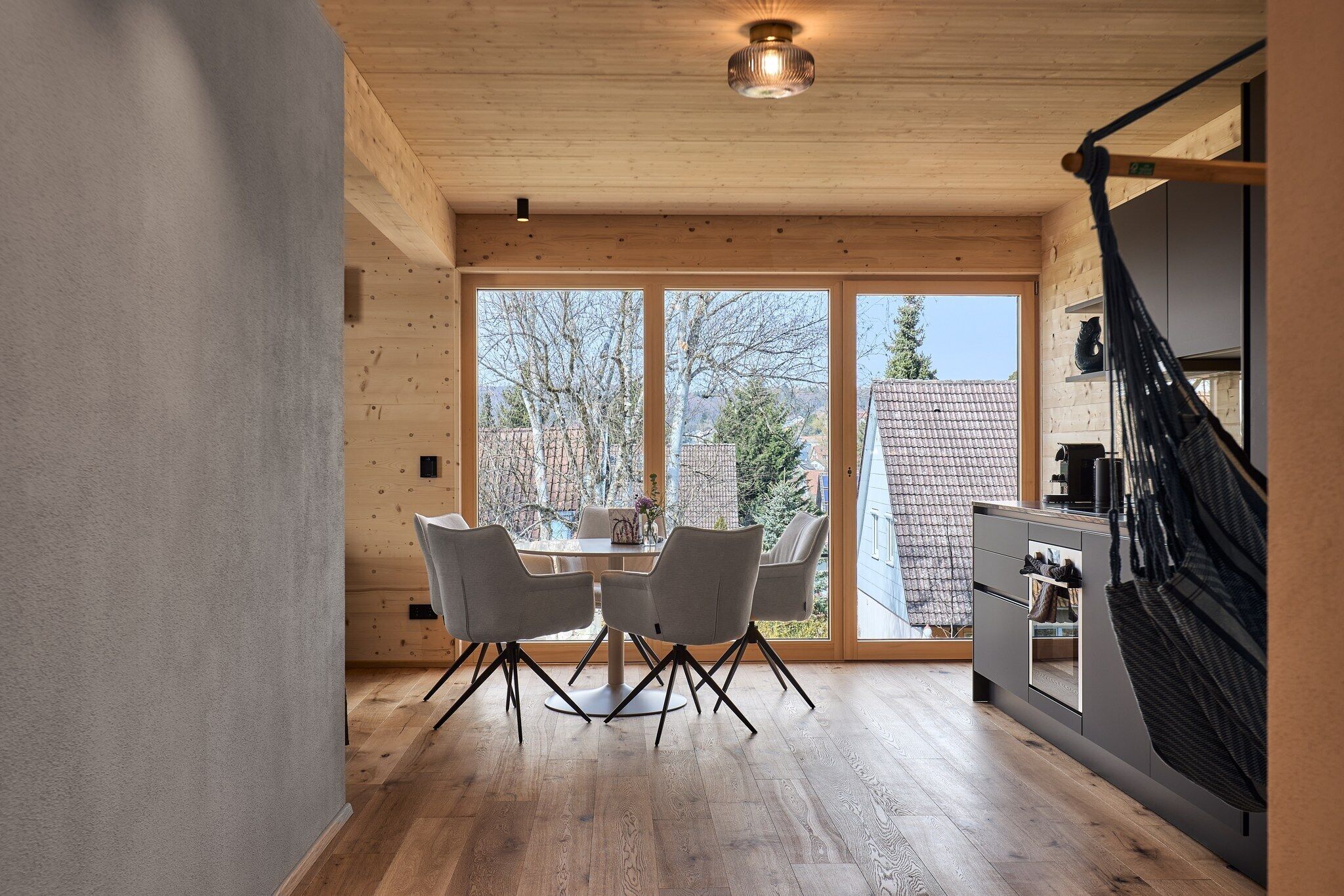 Une cuisine moderne avec des meubles en bois, un coin repas comprenant une table et des chaises, et une grande fenêtre donnant sur l’extérieur.