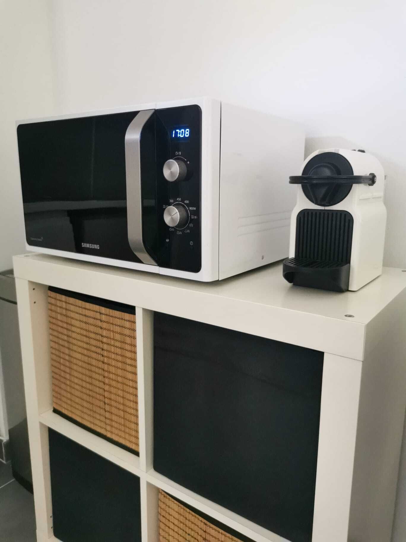 A microwave oven with a digital display and control knobs on a white cabinet with two black doors.