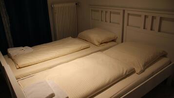 Un lit jumeau avec une tête de lit blanche et un lit simple au design similaire.