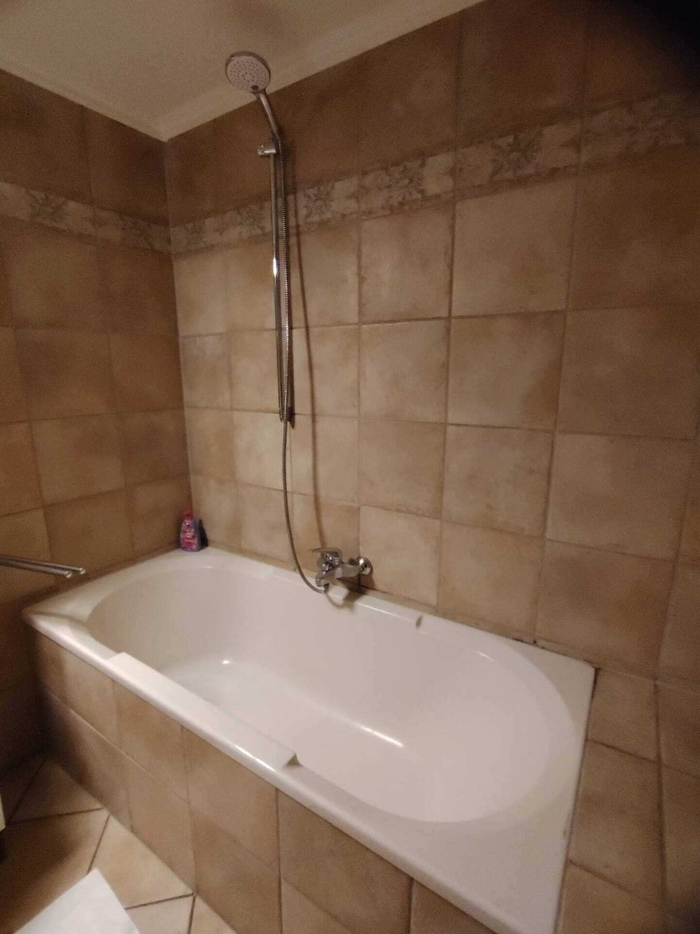 Ein Badezimmer mit Badewanne, Duschkopf und gefliesten Wänden.
