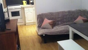 A compact living space with a kitchenette, a sofa, and a small table.