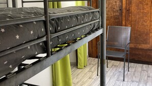 A bunk bed with a star-patterned mattress, a metal chair, and a wooden door in the background.