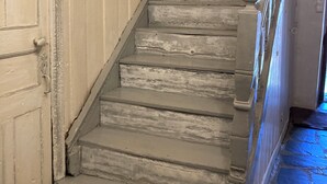 A staircase with wooden steps and a handrail, leading to a door with a white frame.