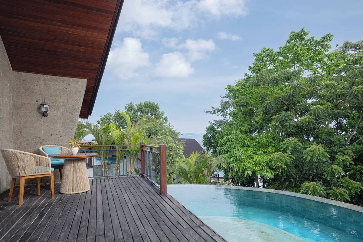 A wooden deck with a pool, chairs, and a table.