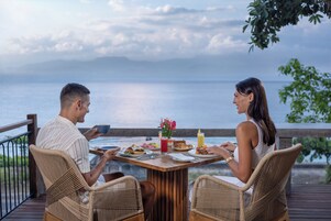 Una pareja cenando en una mesa de madera con vistas al mar.