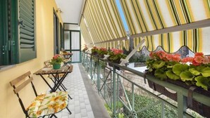Een balkon met tegels, een tafel met stoelen en planten in potten.