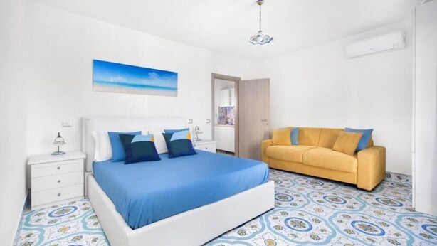 Een slaapkamer met een bed, een bank, een nachtkastje en een schilderij aan de muur.