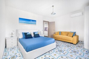 Une chambre à coucher avec un lit, un canapé, une table de chevet et un tableau au mur.