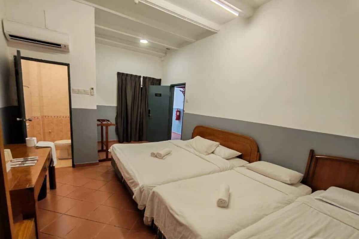Une chambre d’hôtel avec deux lits, un bureau et un appareil de climatisation.
