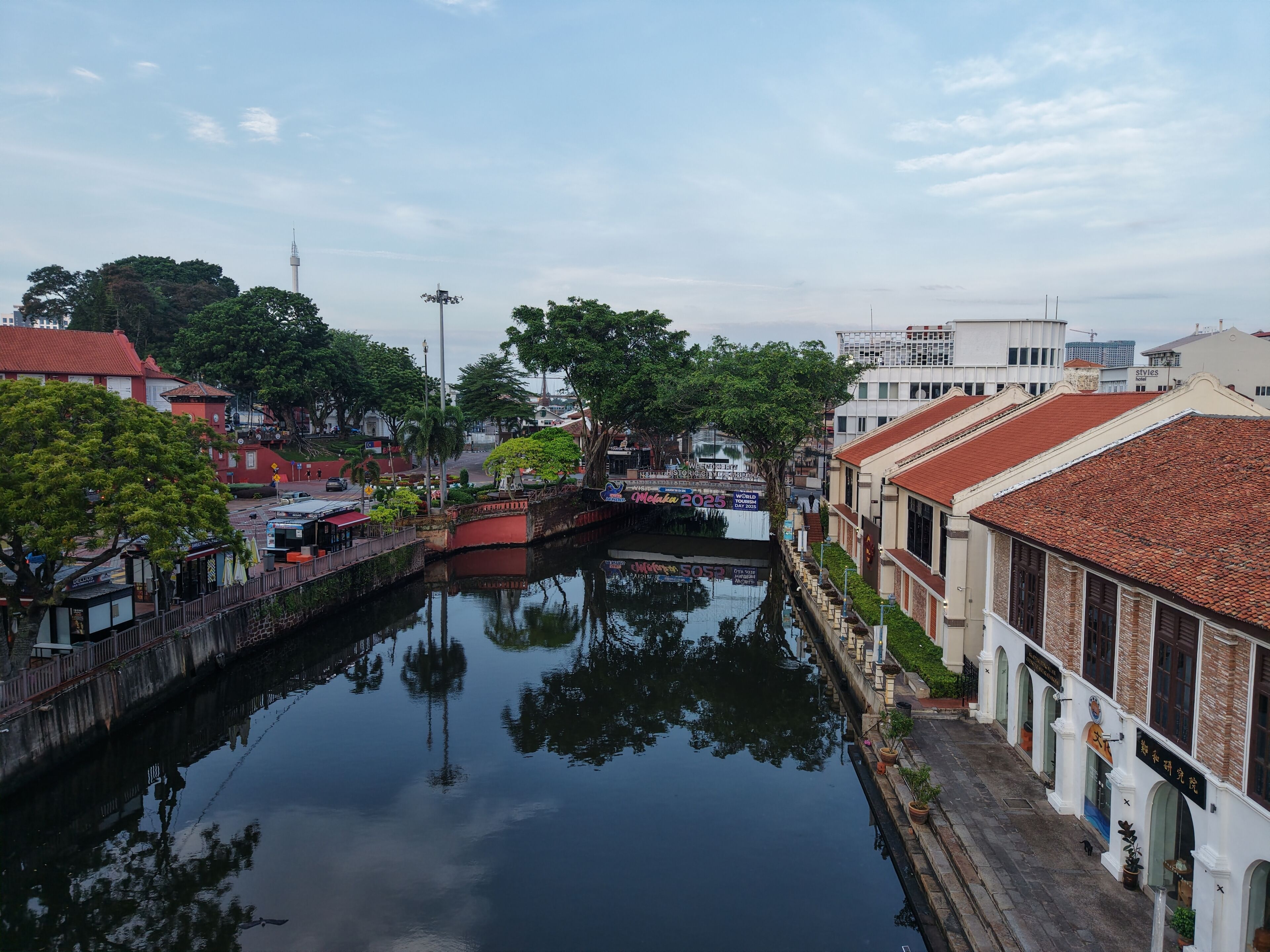 Un canal flanqueado por edificios, entre ellos una hilera de tiendas y un edificio tradicional con tejado de baldosas.