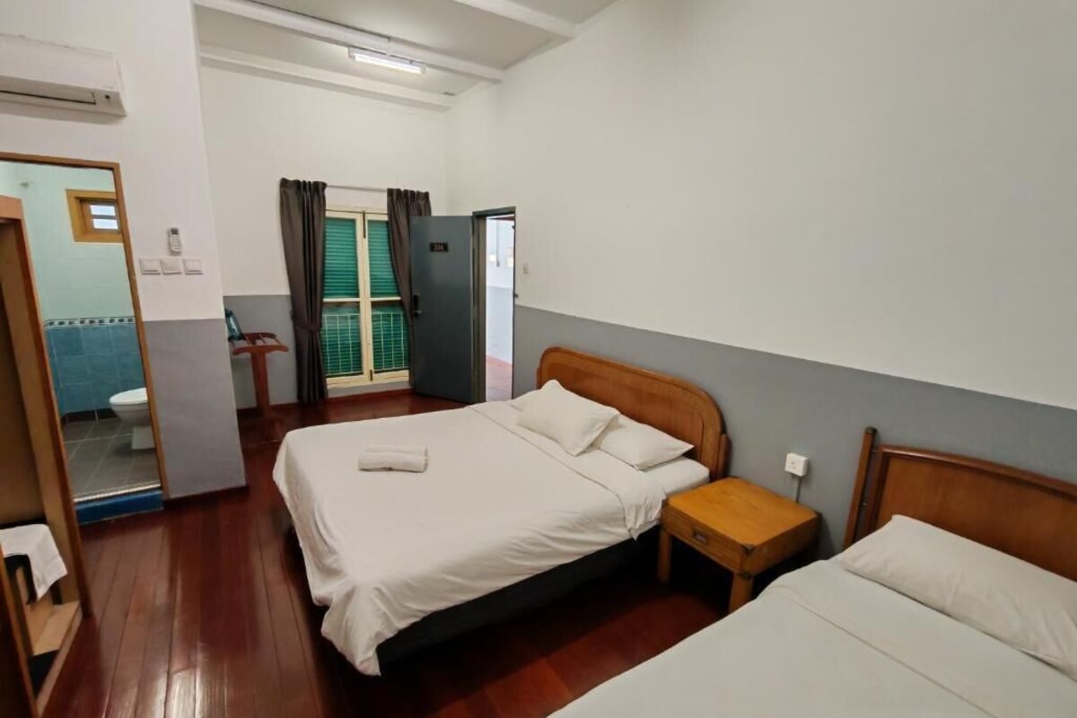 Habitación de hotel con dos camas, cabecero de madera, mesita de noche pequeña y un espejo.