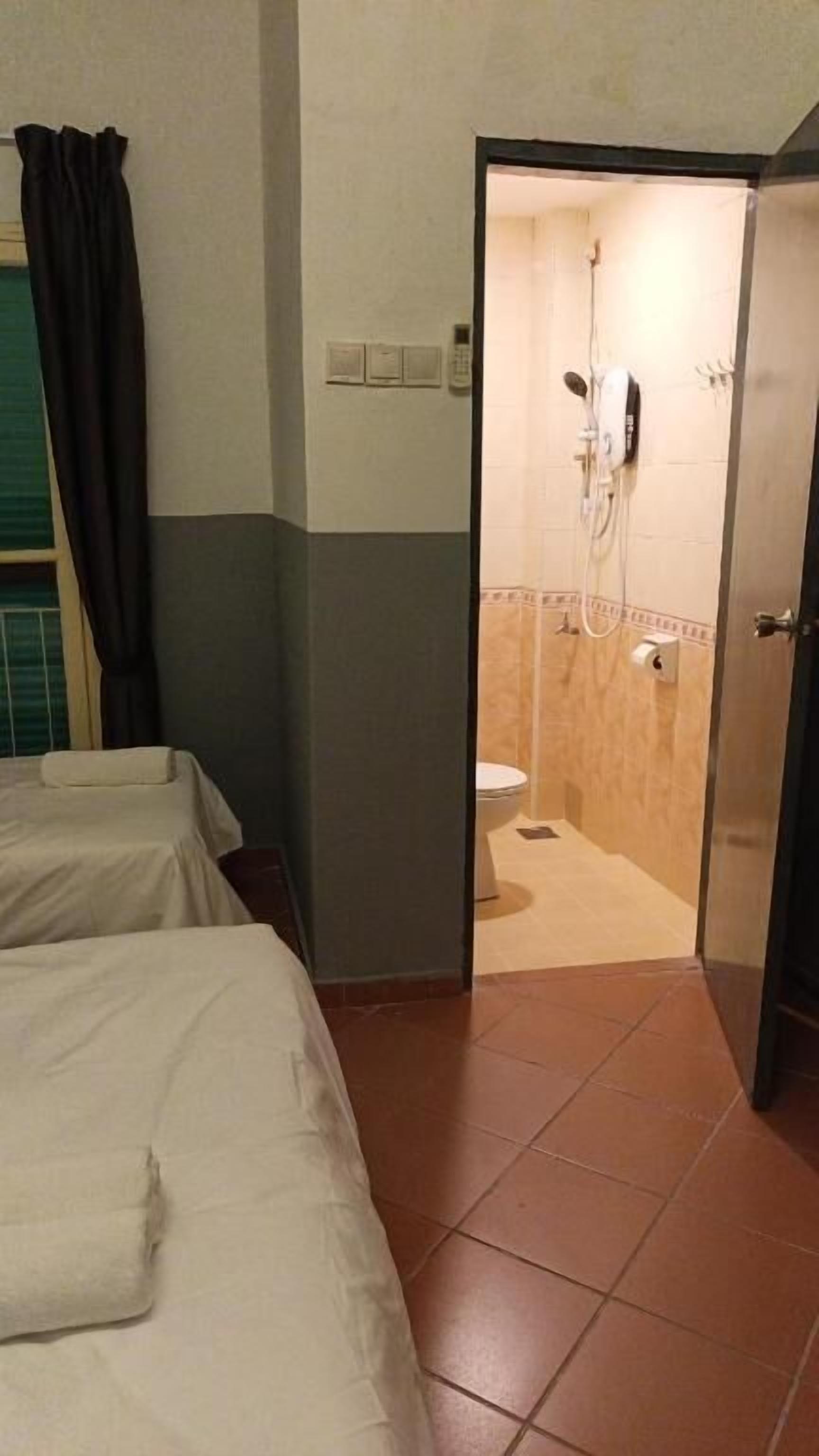 Quarto de hotel com duas camas, banheiro com chuveiro e vaso sanitário.