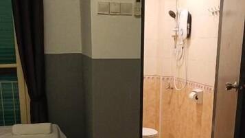 Quarto de hotel com duas camas, banheiro com chuveiro e vaso sanitário.