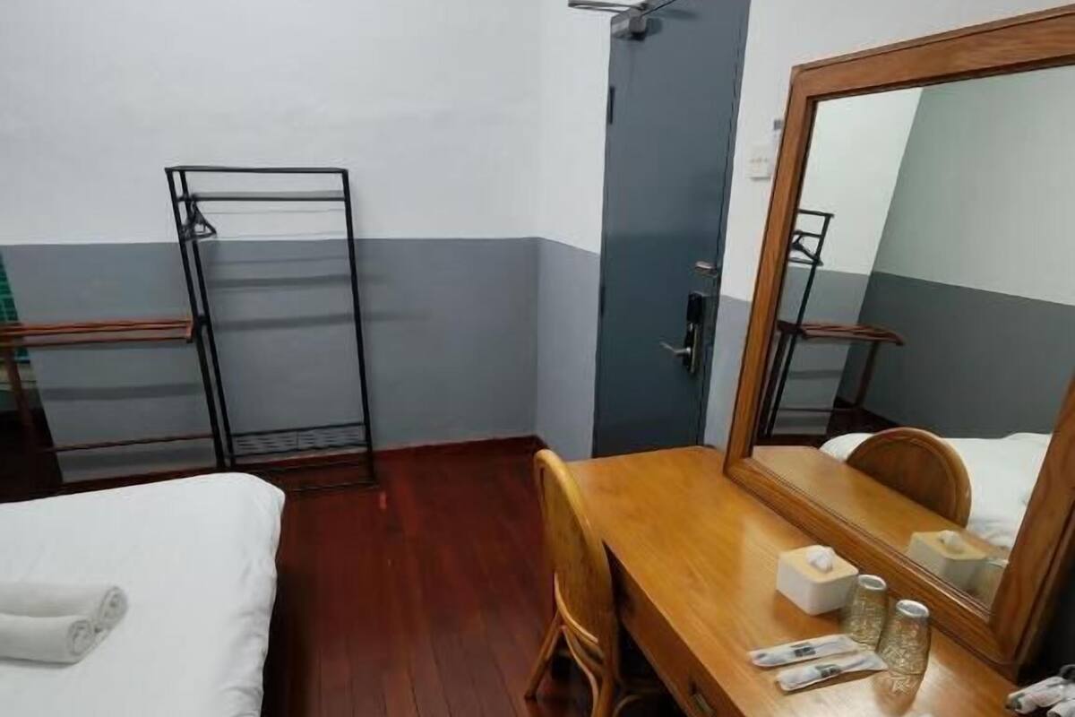 Une chambre d’hôtel avec un bureau en bois, un lit, une chaise, un miroir et une armoire.
