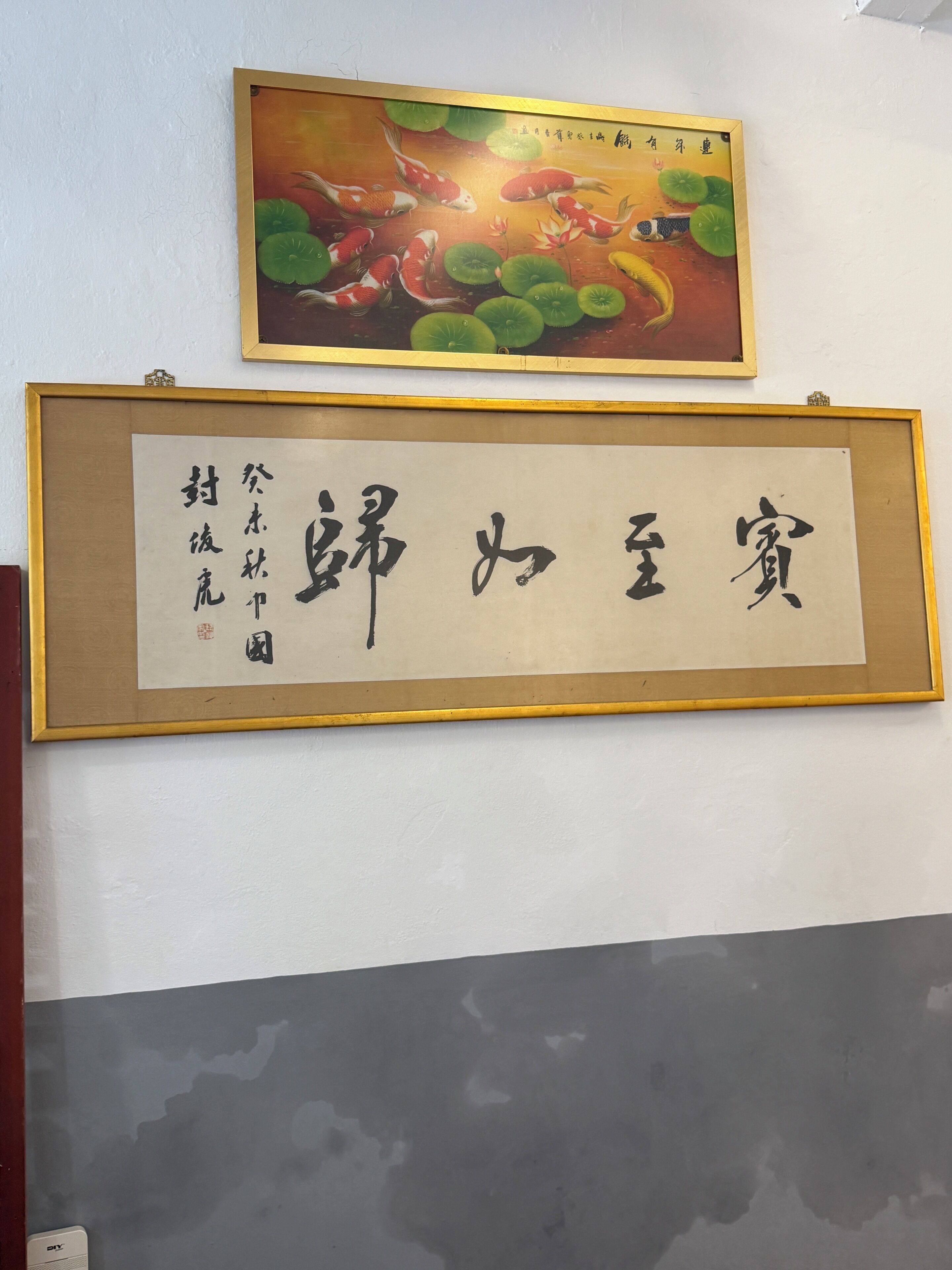A framed calligraphy piece with Chinese characters on a wall.