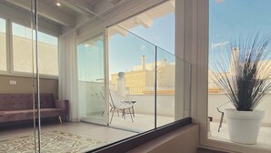 Ein modernes Interieur mit Glastrennwand, einer Couch, einem Sessel und einer Topfpflanze.