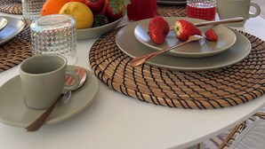 Ein Esstisch mit Obstschale, einer Flasche rotem Getränk und einer Kaffeetasse.