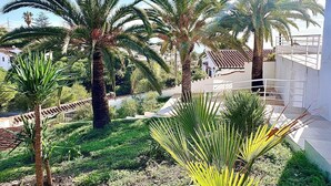 A courtyard with palm trees and a white building with a balcony. - Villa Palmeras - Modern luxury with breathtaking sea view (Caleta de Vélez)