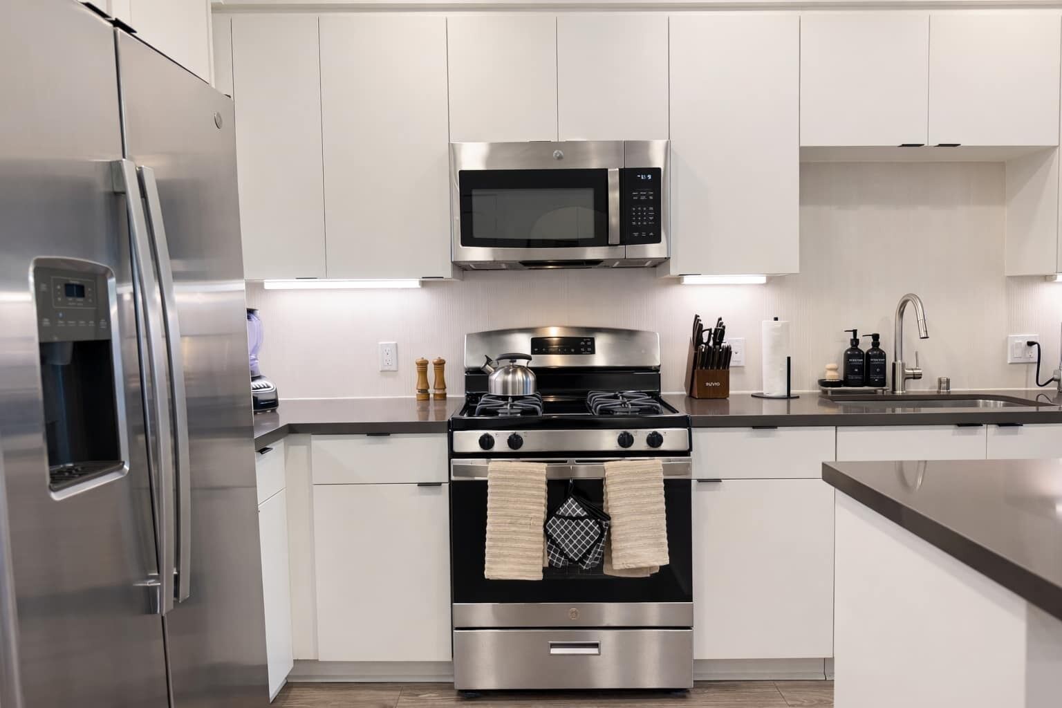 A modern kitchen with stainless steel appliances, a microwave, a stove, and a refrigerator.