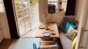Un'accogliente zona pranzo con tavolo apparecchiato per due, un divano con cuscini decorati e una finestra con decorazioni a cuore.