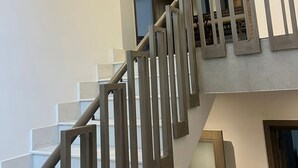 Una escalera moderna con barandillas de metal y un vidrio que da a un nivel superior.