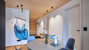 Ein modernes Zimmer mit einem runden Tisch, Stühlen, einem Hängesessel und einer Tür.