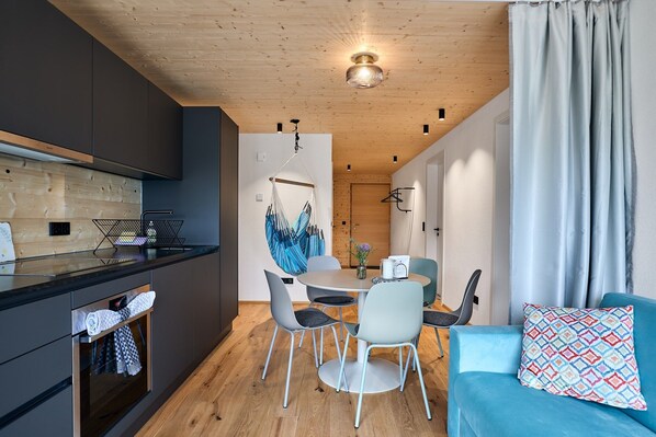 Una cocina moderna con armarios oscuros, techo de madera y un comedor con una mesa redonda y sillas.